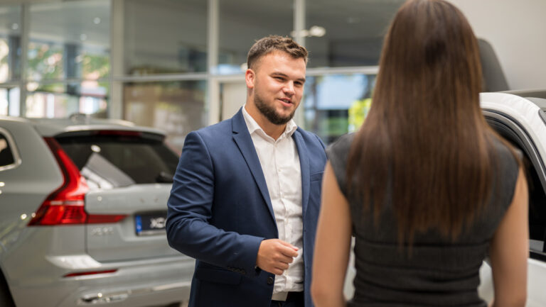 Verkaufsberater im Autohaus Erdmannsky berät eine Kundin im Showroom neben einem Fahrzeug